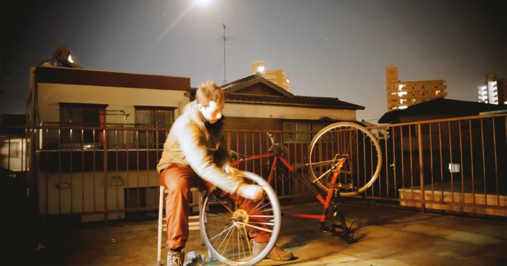 Me on my apartment rooftop during a solo travel in Japan—fixing my bike, questioning everything, and somehow still believing I could ride across a country I hadn’t even explored yet
